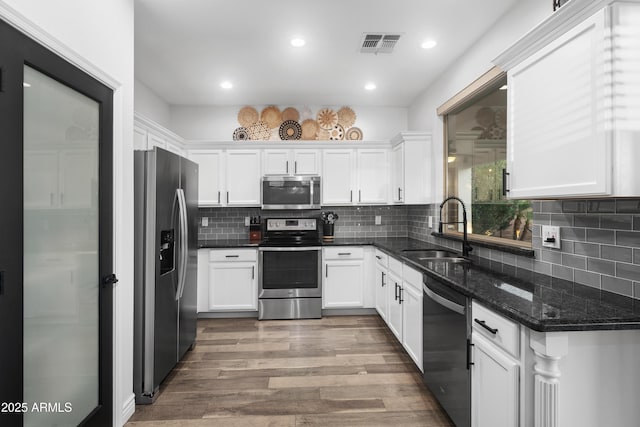 kitchen featuring a sink, appliances with stainless steel finishes, white cabinets, and visible vents
