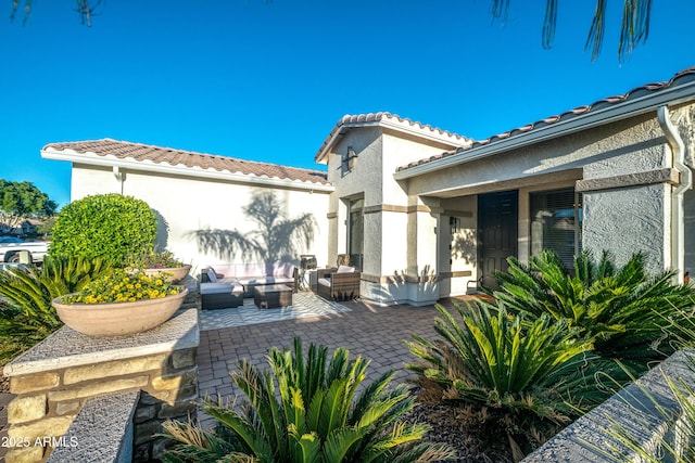 exterior space with stucco siding, outdoor lounge area, a patio area, and a tile roof