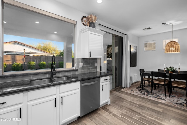 kitchen with stainless steel dishwasher, a healthy amount of sunlight, a sink, and light wood finished floors