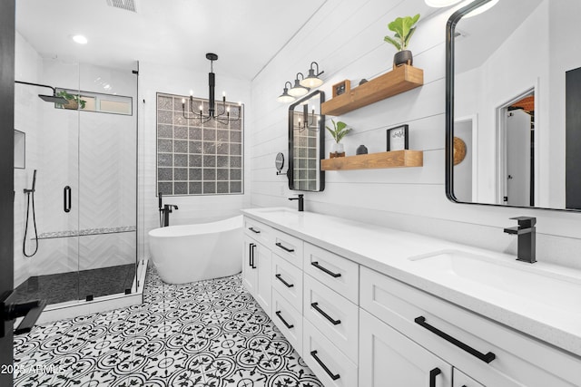 full bath featuring a notable chandelier, a sink, double vanity, a freestanding tub, and a shower stall