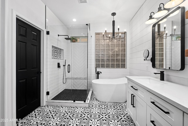 bathroom with vanity, a soaking tub, a shower stall, and a chandelier