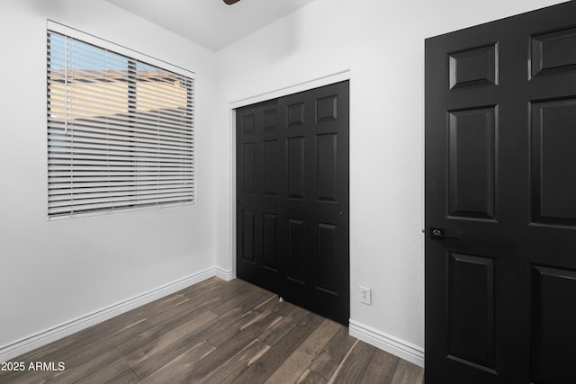 interior space featuring baseboards, dark wood-style floors, and a closet