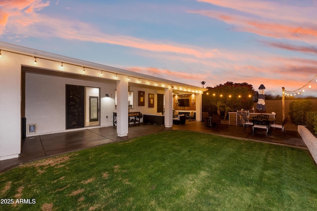 rear view of property featuring a lawn, stucco siding, a patio area, and outdoor lounge area