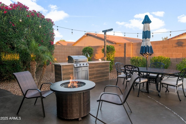 view of patio featuring fence, outdoor dining space, a grill, and a fire pit