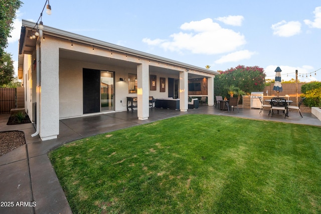 rear view of property featuring a lawn, fence, a patio area, and stucco siding