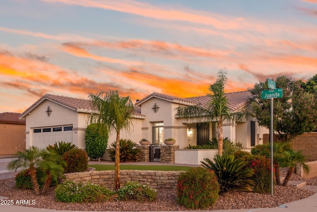 mediterranean / spanish-style house with a tiled roof, an attached garage, and stucco siding