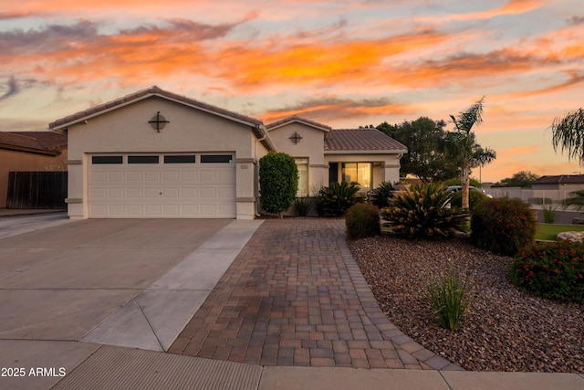 view of front facade with a garage, stucco siding, driveway, and a tiled roof