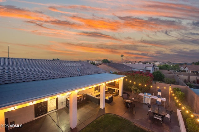 patio terrace at dusk with a fenced backyard and outdoor dining area