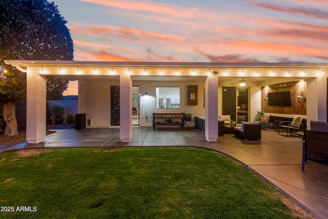 rear view of property with a yard, a patio, an outdoor hangout area, and stucco siding