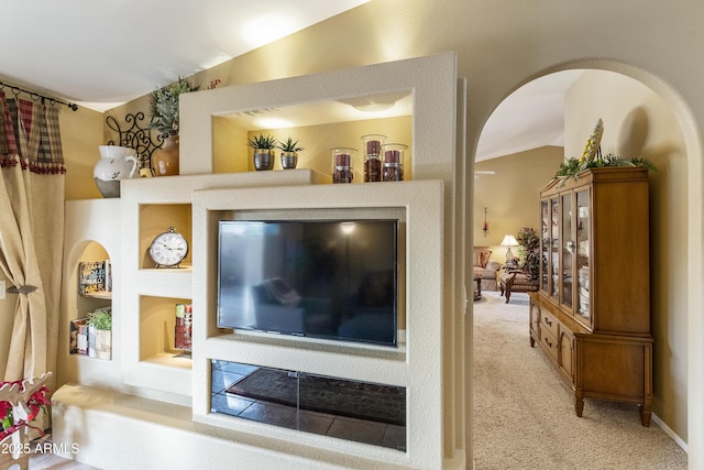 carpeted living room with built in features and lofted ceiling