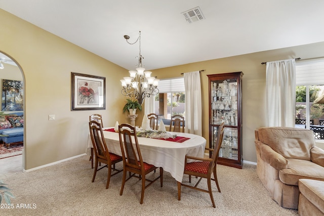 dining room with a chandelier, light colored carpet, and vaulted ceiling