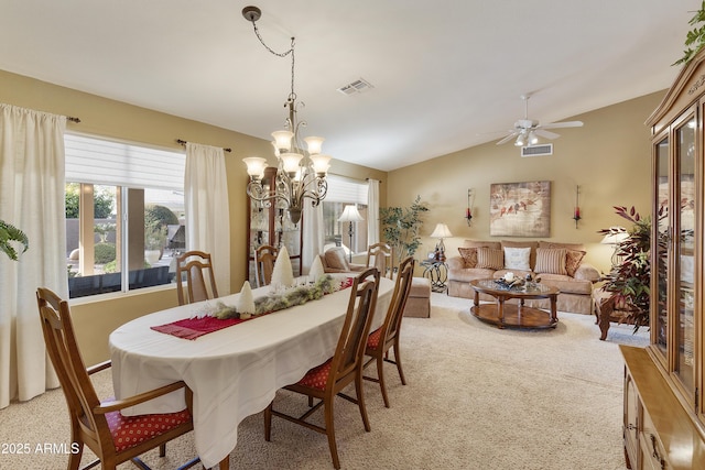 carpeted dining room featuring ceiling fan with notable chandelier and lofted ceiling