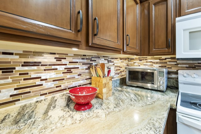 kitchen featuring light stone countertops, white appliances, and backsplash