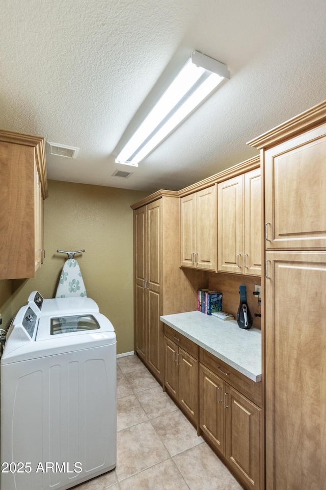 laundry room featuring separate washer and dryer, light tile patterned floors, cabinets, and a textured ceiling