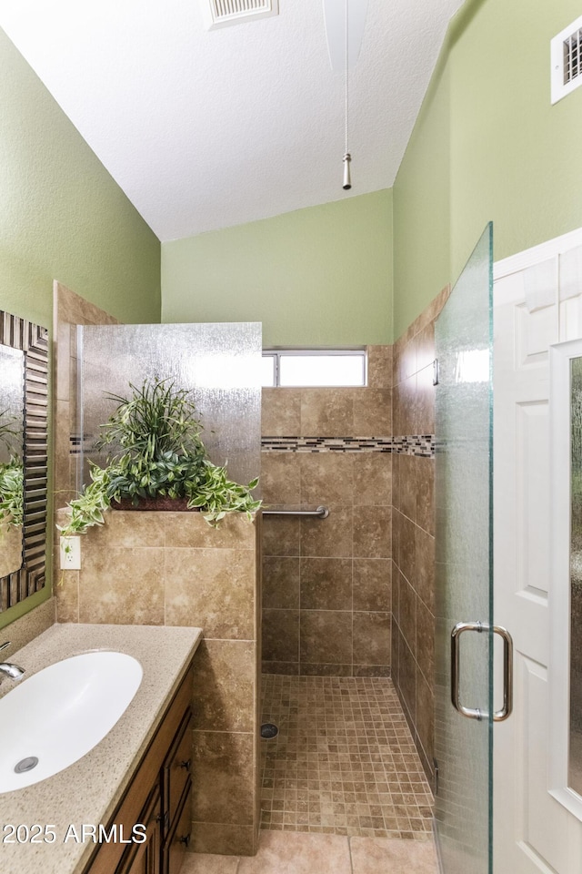 bathroom with tile patterned floors, a shower with door, vanity, and a textured ceiling