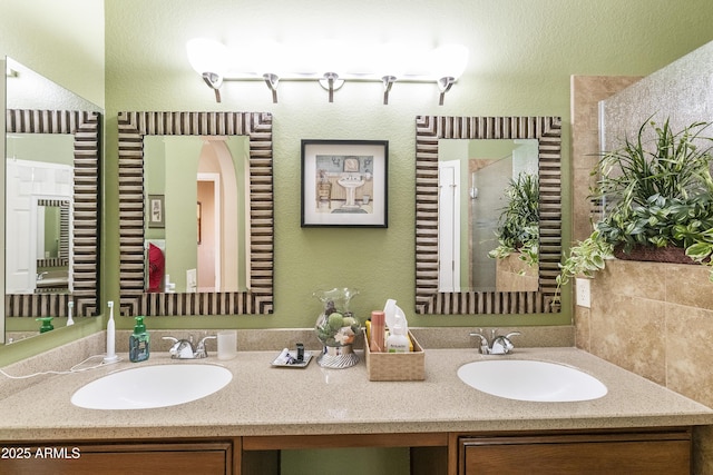 bathroom featuring a shower with door and vanity