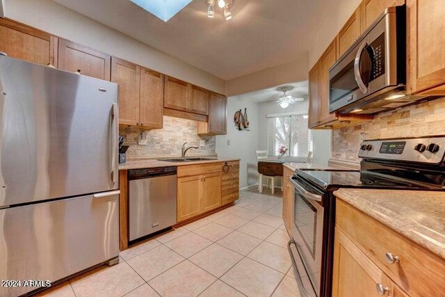 kitchen featuring ceiling fan, tasteful backsplash, stainless steel appliances, sink, and light tile patterned floors