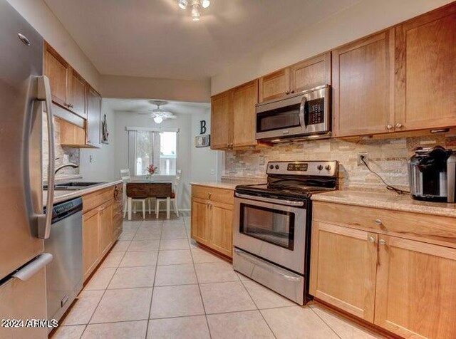 kitchen featuring light tile patterned flooring, ceiling fan, stainless steel appliances, decorative backsplash, and sink