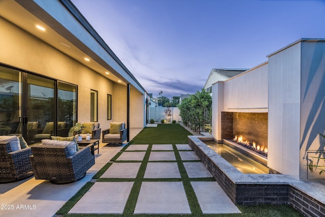 6329 N 10th Dr, Phoenix, AZ 85013 - patio terrace at dusk with a lawn, a warm lit fireplace, and fence