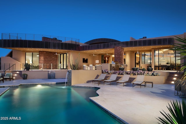 pool at dusk with pool water feature and a patio