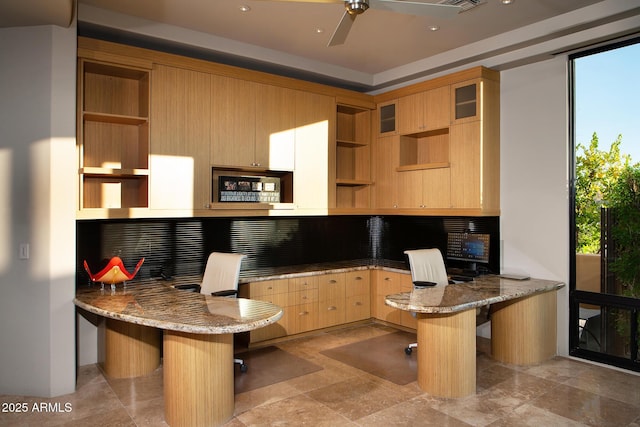 kitchen featuring a kitchen bar, kitchen peninsula, light stone countertops, and light brown cabinets