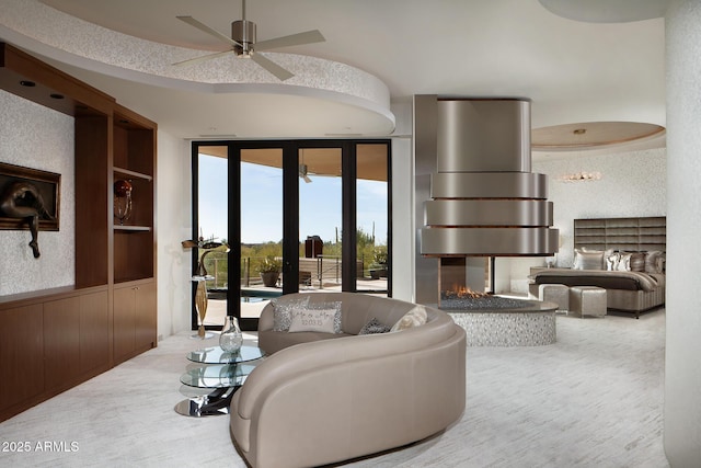 living room featuring a multi sided fireplace, built in shelves, ceiling fan, and a healthy amount of sunlight