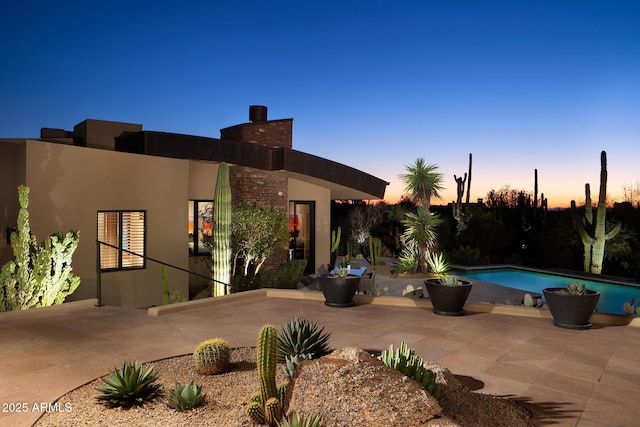 pool at dusk featuring a patio