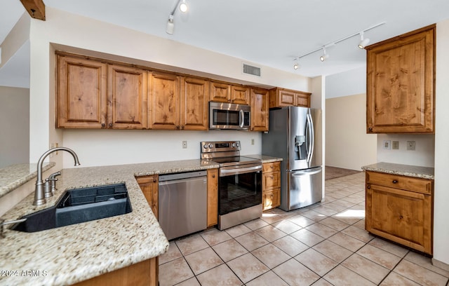 kitchen featuring light tile patterned floors, stainless steel appliances, light stone counters, and sink