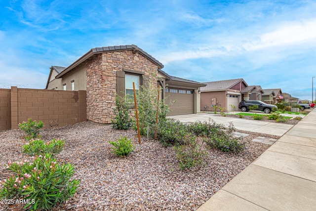 view of front facade with stucco siding, fence, a garage, stone siding, and driveway