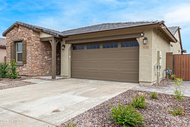 view of front of house featuring concrete driveway, stone siding, a tile roof, an attached garage, and stucco siding