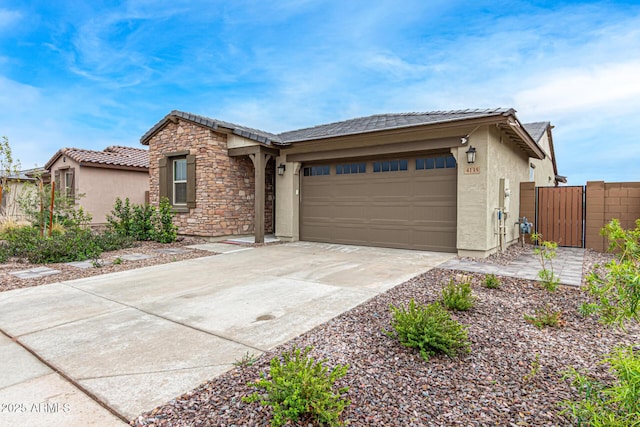 single story home featuring an attached garage, stone siding, concrete driveway, a gate, and stucco siding