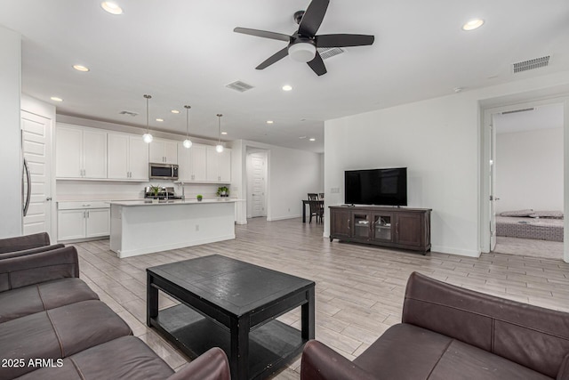 living room with wood tiled floor, visible vents, and recessed lighting