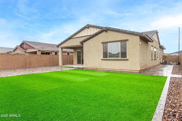 back of house featuring central AC unit, a lawn, a fenced backyard, a patio area, and stucco siding