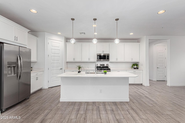 kitchen featuring appliances with stainless steel finishes, white cabinets, light countertops, and light wood finished floors