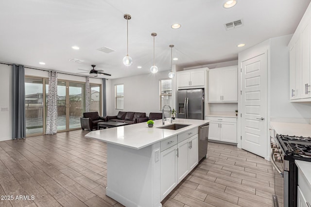 kitchen featuring stainless steel appliances, light countertops, a sink, and visible vents