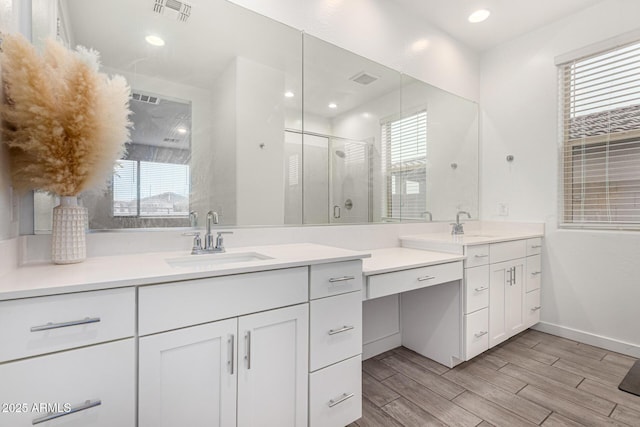 bathroom featuring a stall shower, visible vents, a wealth of natural light, and a sink