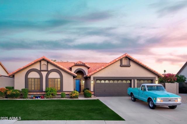 mediterranean / spanish house featuring a garage, concrete driveway, a yard, stucco siding, and a tile roof