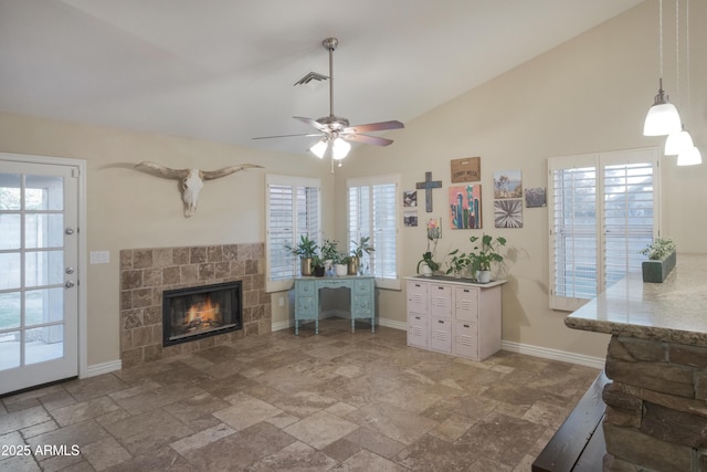 living area featuring a fireplace, stone tile flooring, a ceiling fan, plenty of natural light, and high vaulted ceiling