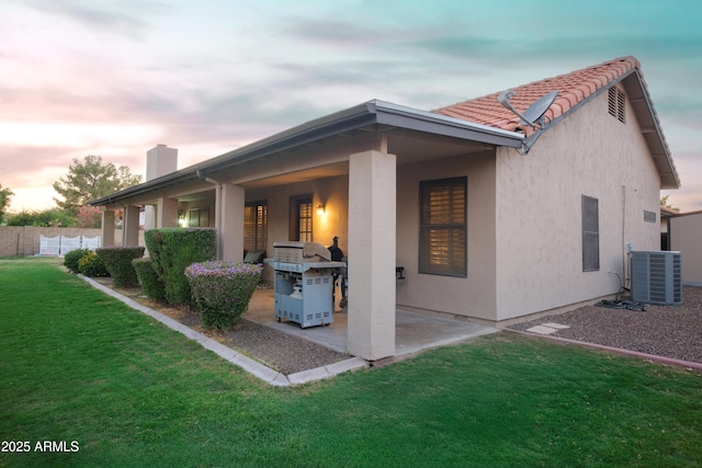back of house featuring central AC unit, a chimney, a patio, stucco siding, and a tiled roof