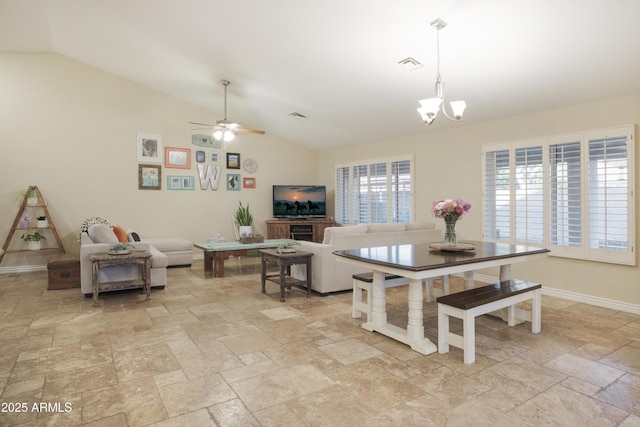 dining area featuring stone tile floors, lofted ceiling, a chandelier, a ceiling fan, and baseboards
