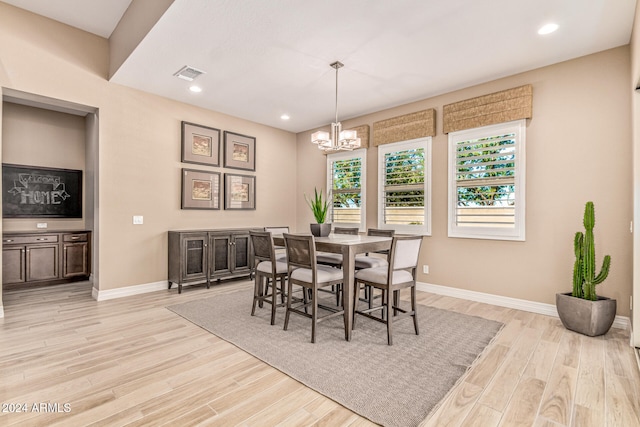 dining area featuring light wood-type flooring and a notable chandelier