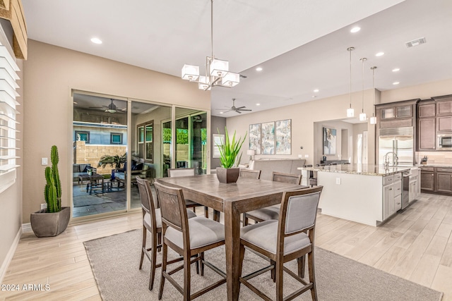 dining room with ceiling fan with notable chandelier and light wood-type flooring