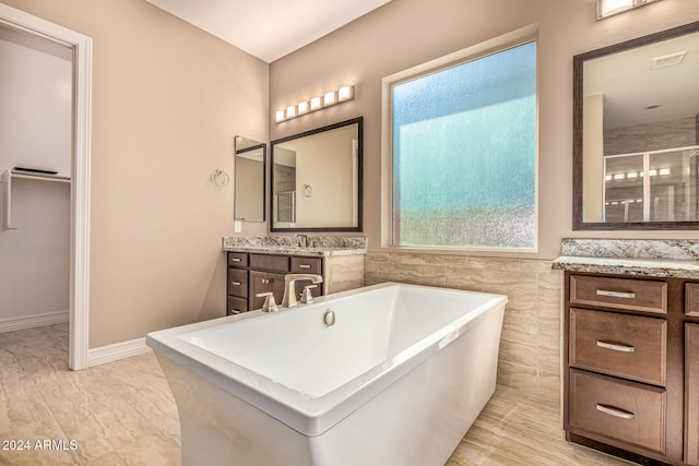 bathroom with separate shower and tub, vanity, and tile walls