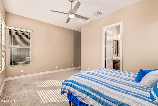 bedroom featuring ceiling fan, light colored carpet, and connected bathroom