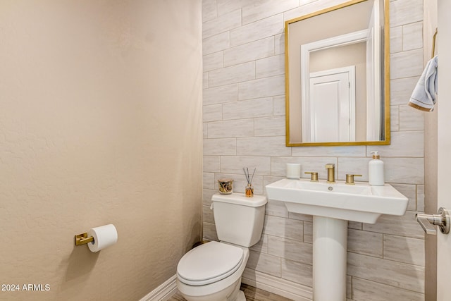 bathroom featuring toilet and tile walls