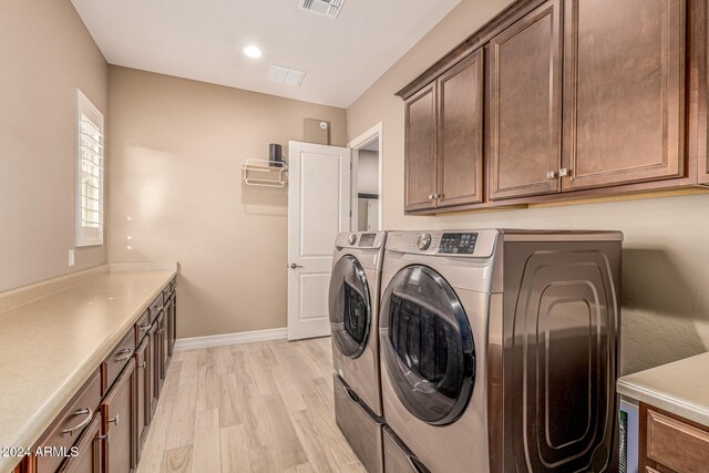 laundry area with cabinets, light wood-type flooring, and washing machine and dryer