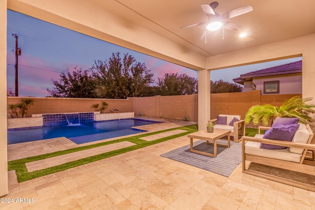 pool at dusk featuring outdoor lounge area, pool water feature, ceiling fan, and a patio area