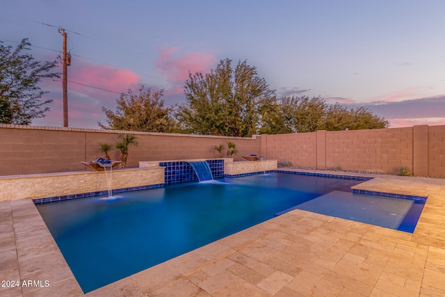 pool at dusk featuring pool water feature