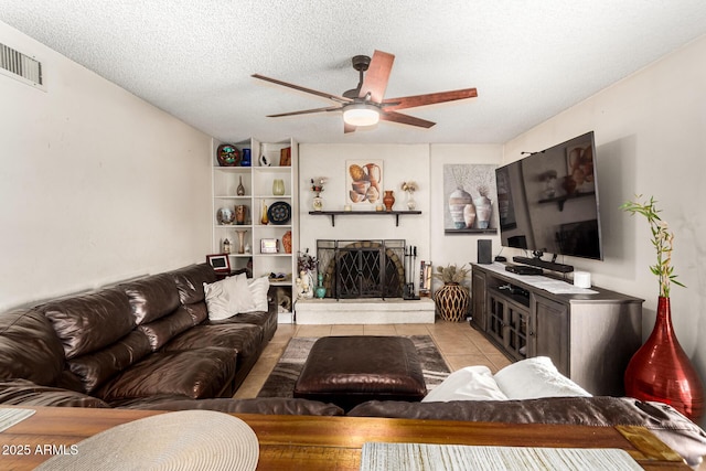 living room featuring light tile patterned flooring, ceiling fan, and a textured ceiling