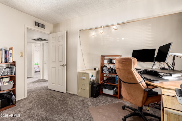 office area featuring dark colored carpet, rail lighting, and a textured ceiling